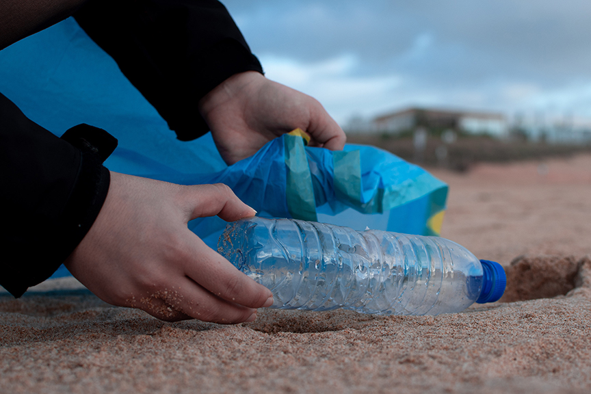 Picking up a plastic bottle off of a beach